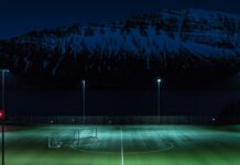 PSG-OL en Ligue 1 : le choc de la 8e journée menacé de report Photo d'illustration : Terrain synthétique vide éclairé par des mâts d'éclairage la nuit